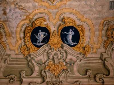 Attorno alla scena otto ovali mostrano le raffigurazioni delle muse con in mano i loro attributi iconografici: maschere, strumenti musicali e pergamene